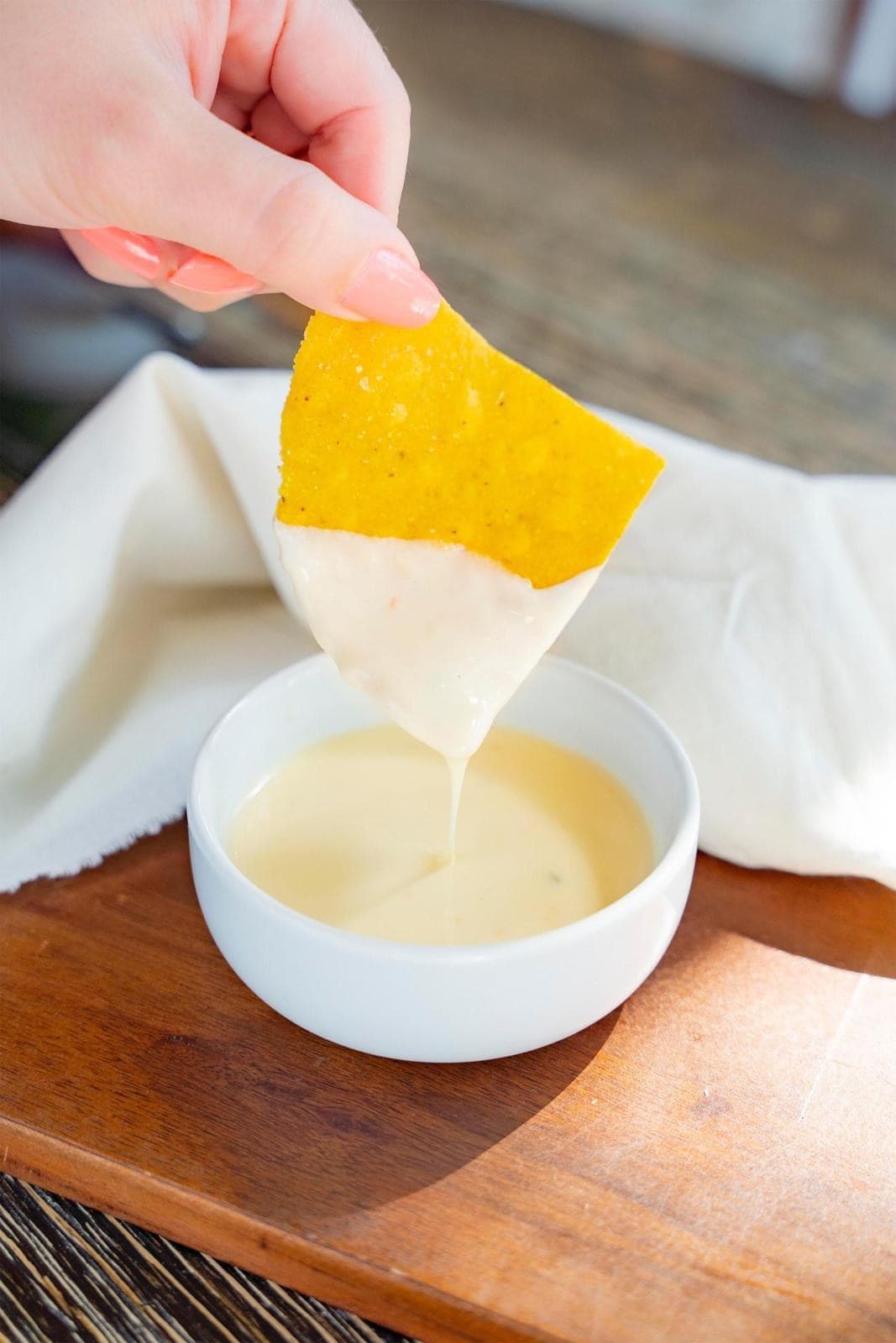 A tortilla chip dipped into a cup of warm white queso
