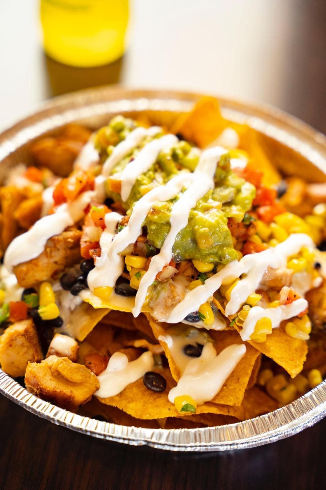 Loaded nachos with queso, crema, guacamole, black beans and corn